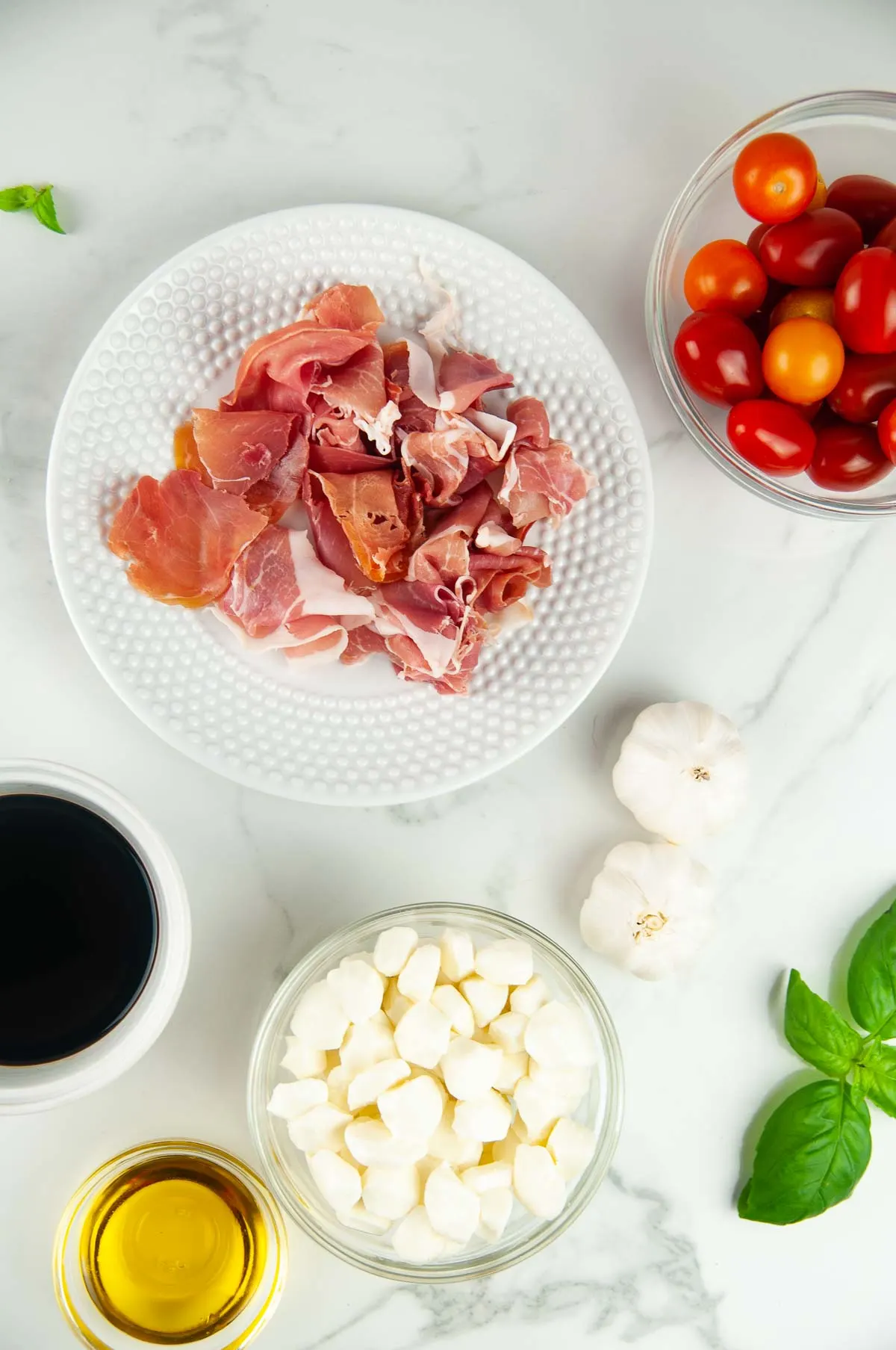Ingredients for Prosciutto Caprese Skewers: Cherry Tomatoes, Prosciutto, Mozzarella, Balsamic, and Fresh Basil