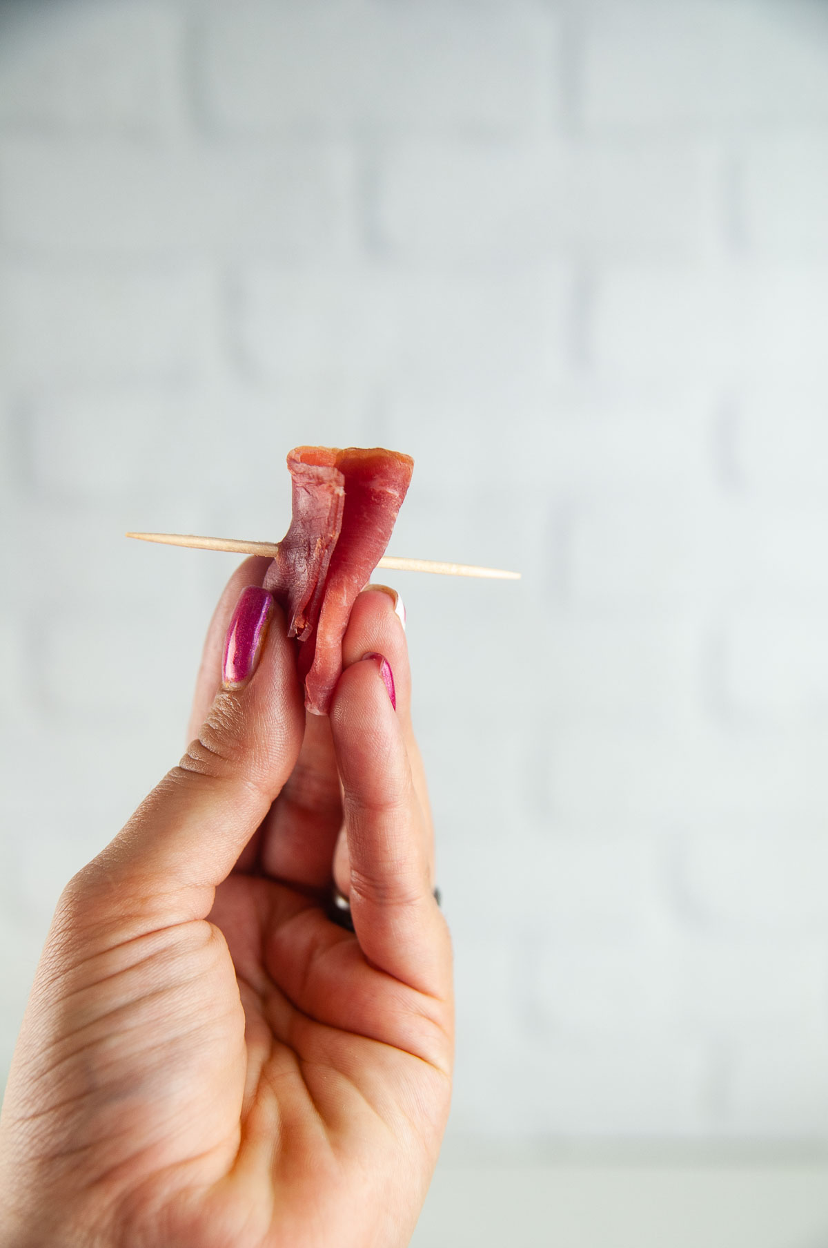 Fold and roll up a piece of prosciutto and thread a toothpick through it