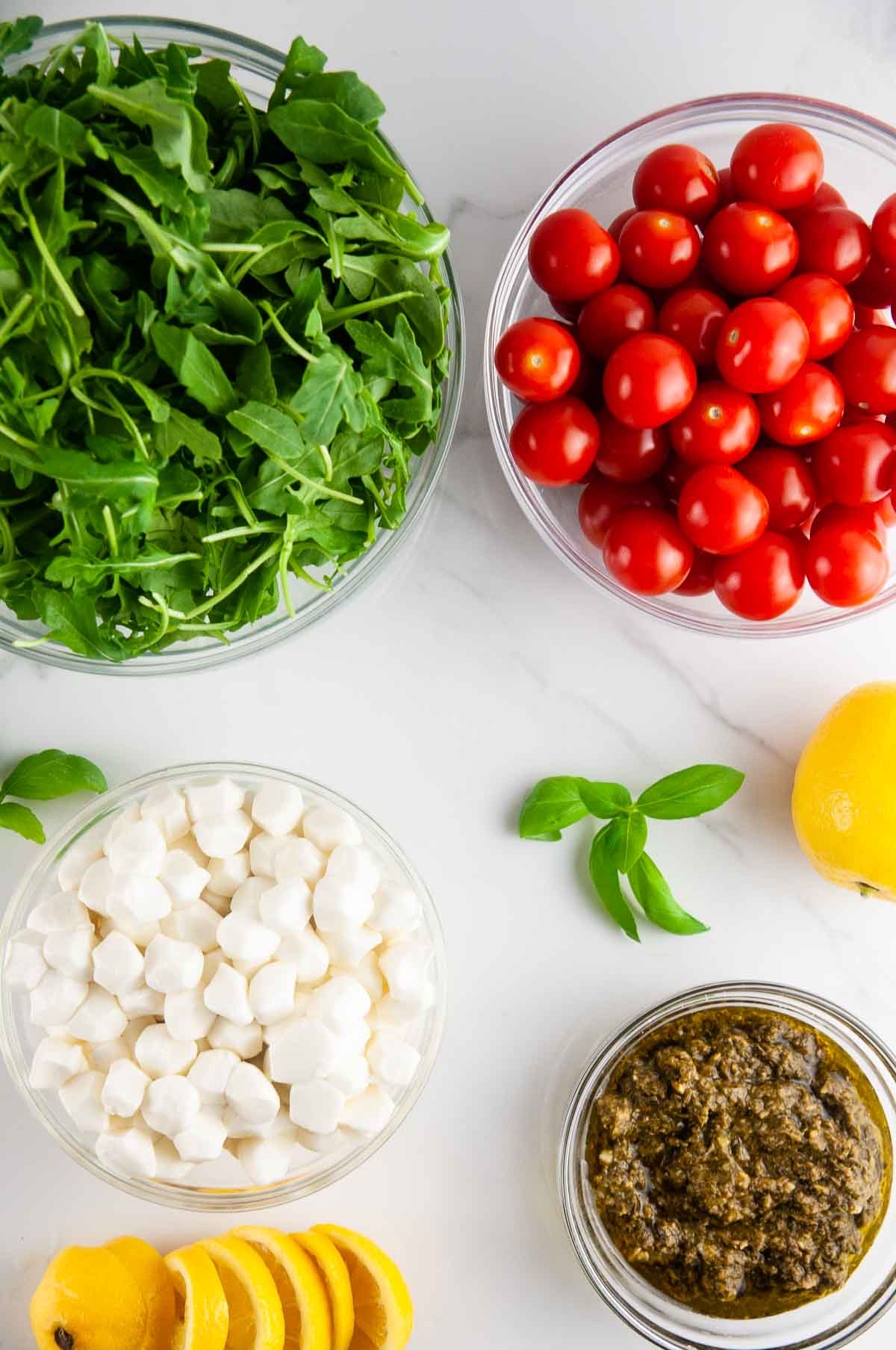 Ingredients for Pesto Caprese Salad: Arugula, Tomatoes, Mozzarella, Basil, Pesto, Lemon