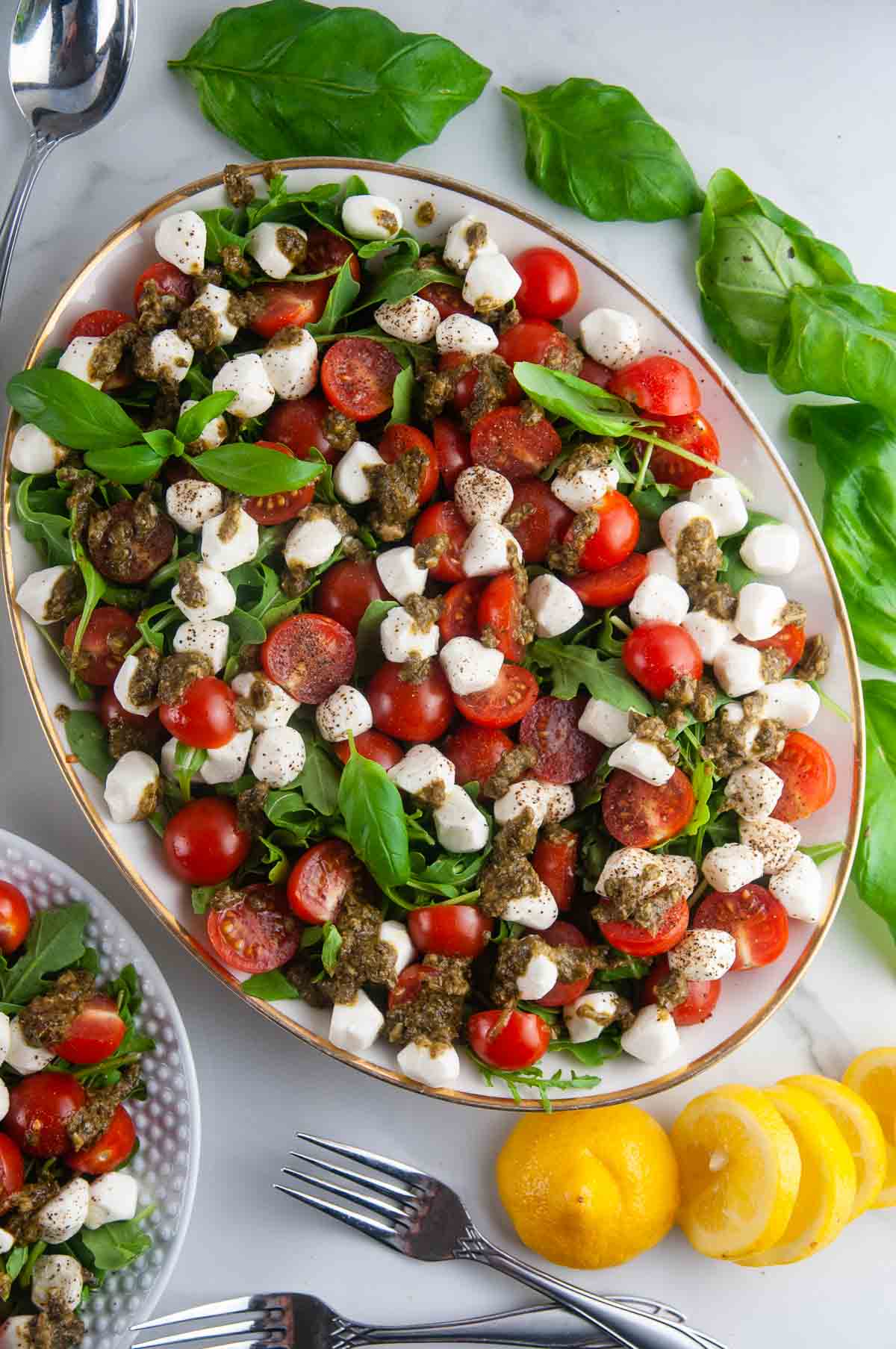 Easy pesto Caprese salad features creamy fresh mozzarella, sweet cherry tomatoes, and aromatic basil all served over sharp arugula and drizzled with lemon pesto.