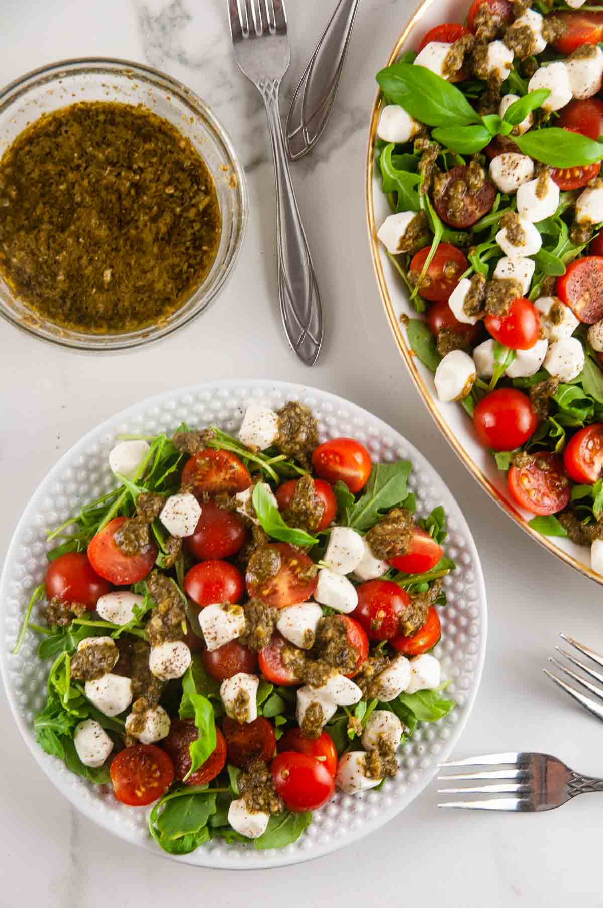 Easy pesto Caprese salad features creamy fresh mozzarella, sweet cherry tomatoes, and aromatic basil all served over sharp arugula and drizzled with lemon pesto.