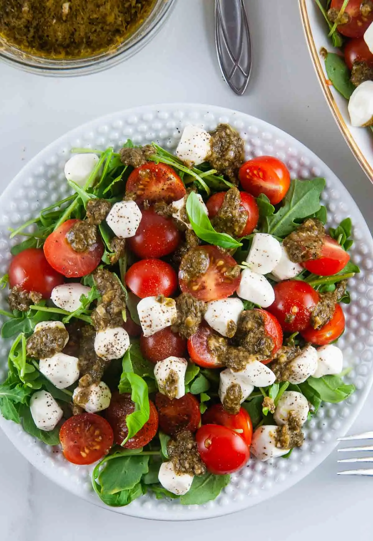 Easy pesto Caprese salad features creamy fresh mozzarella, sweet cherry tomatoes, and aromatic basil all served over sharp arugula and drizzled with lemon pesto.