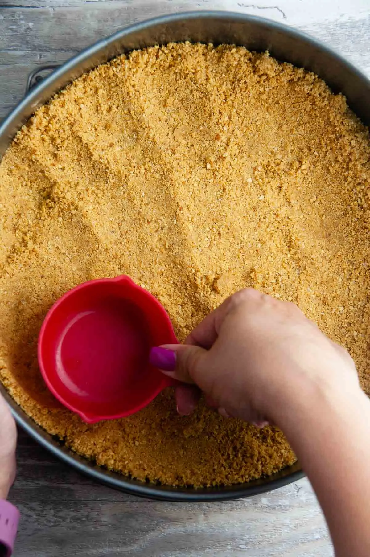 Use a measuring cup to press the graham cracker crust evenly into the plate and up the sides