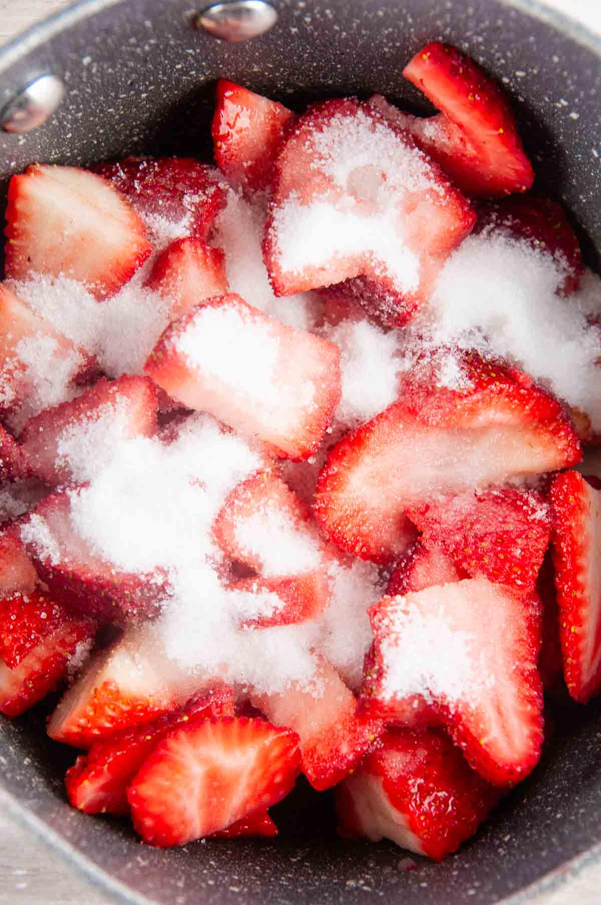 Sliced strawberries in a sauce pan with sugar and lemon juice