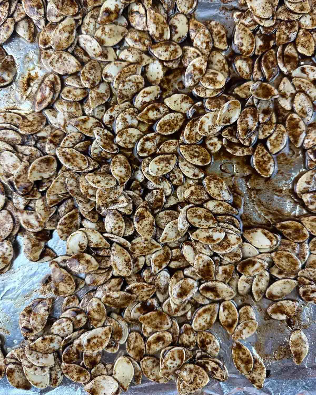 Spread the honeyed, seasoned pumpkin seeds out over a cookie sheet.