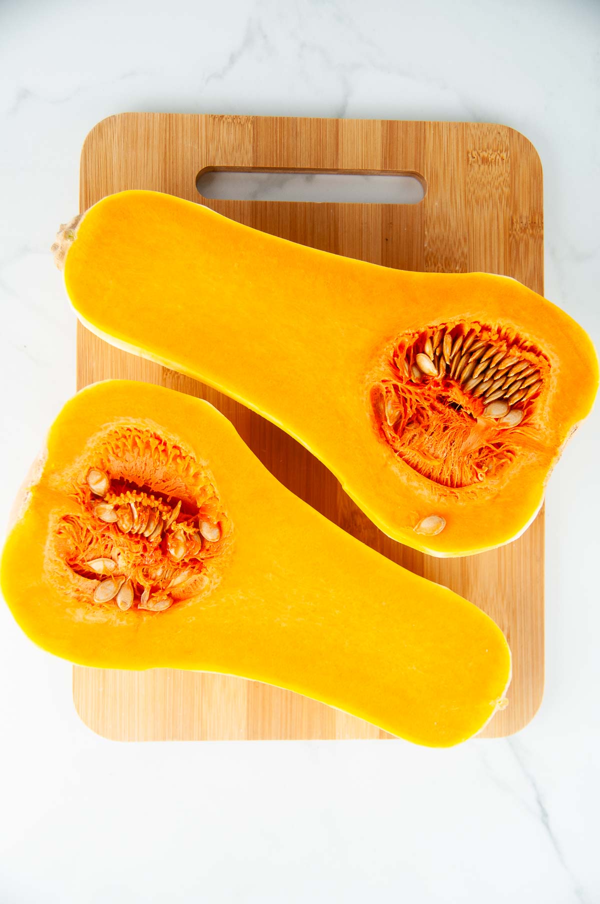 Cut the butternut squash in half to access the seeds in the cavity.