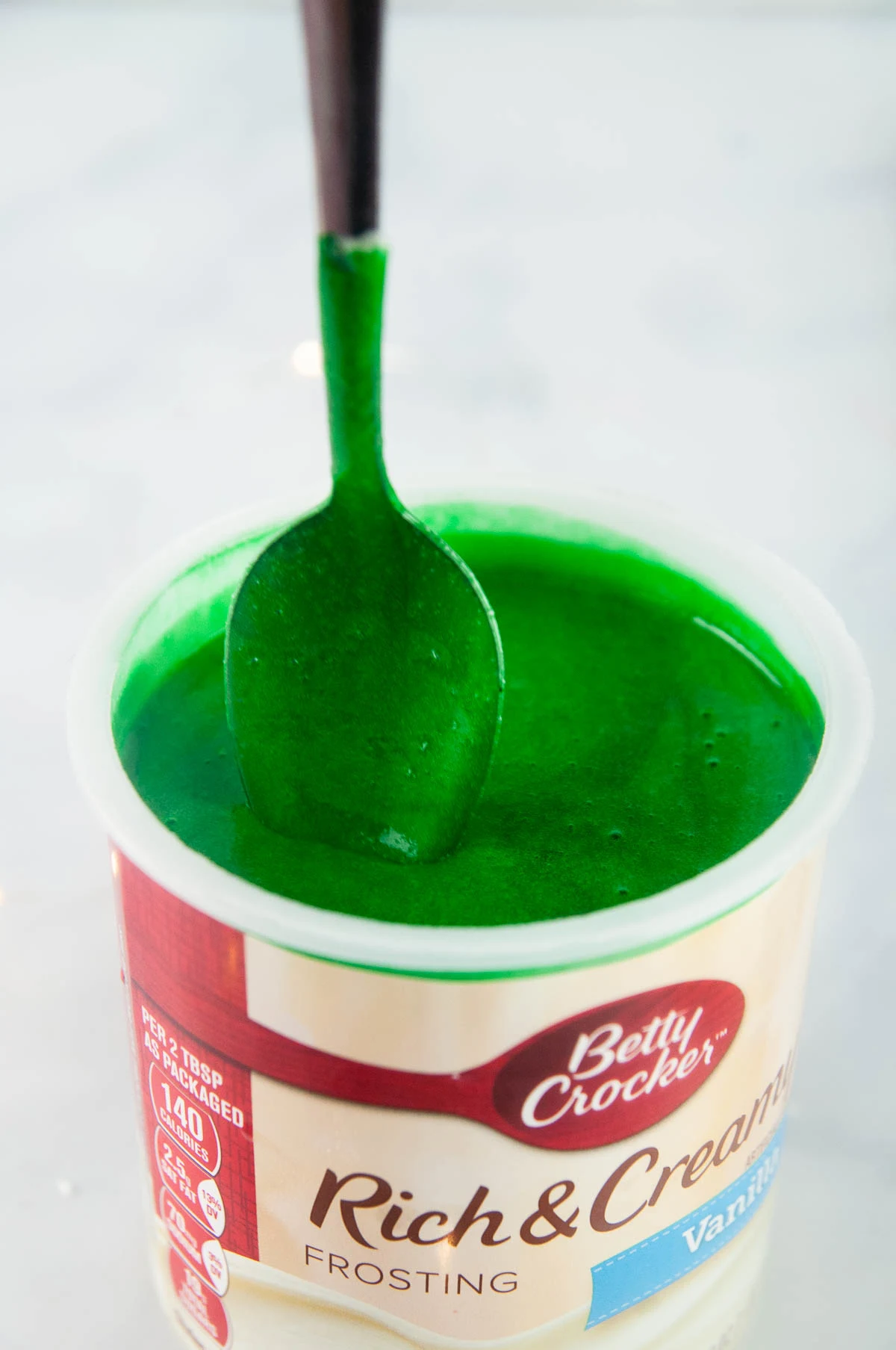 Stir in a few drops of green food coloring into microwaved vanilla frosting until it reaches your desired color.