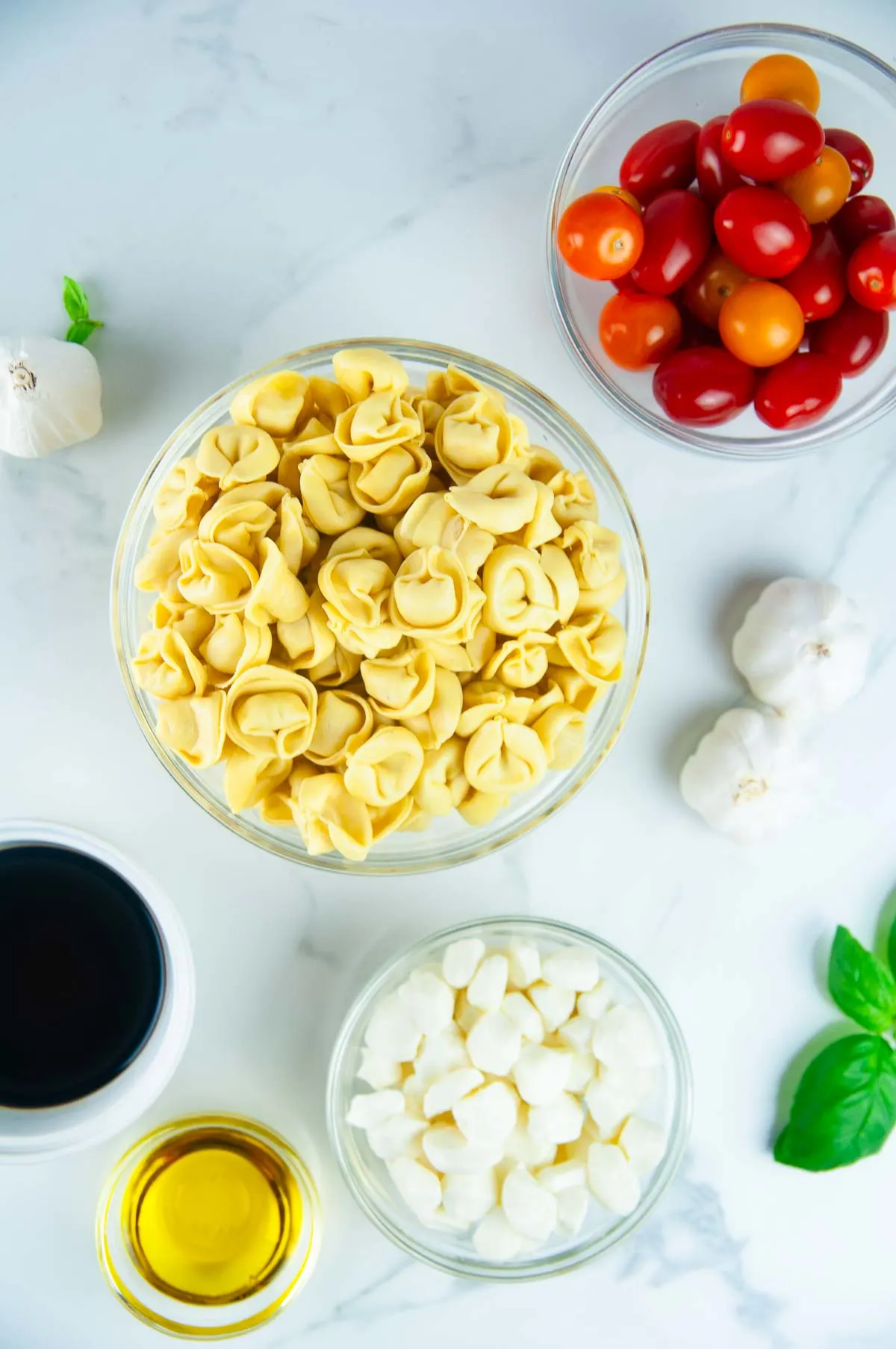 Ingredients for Tortellini Caprese Skewers: Tortellini, Cherry Tomatoes, Mini Mozzarella Balls, Basil, Balsamic Vinegar, and Honey