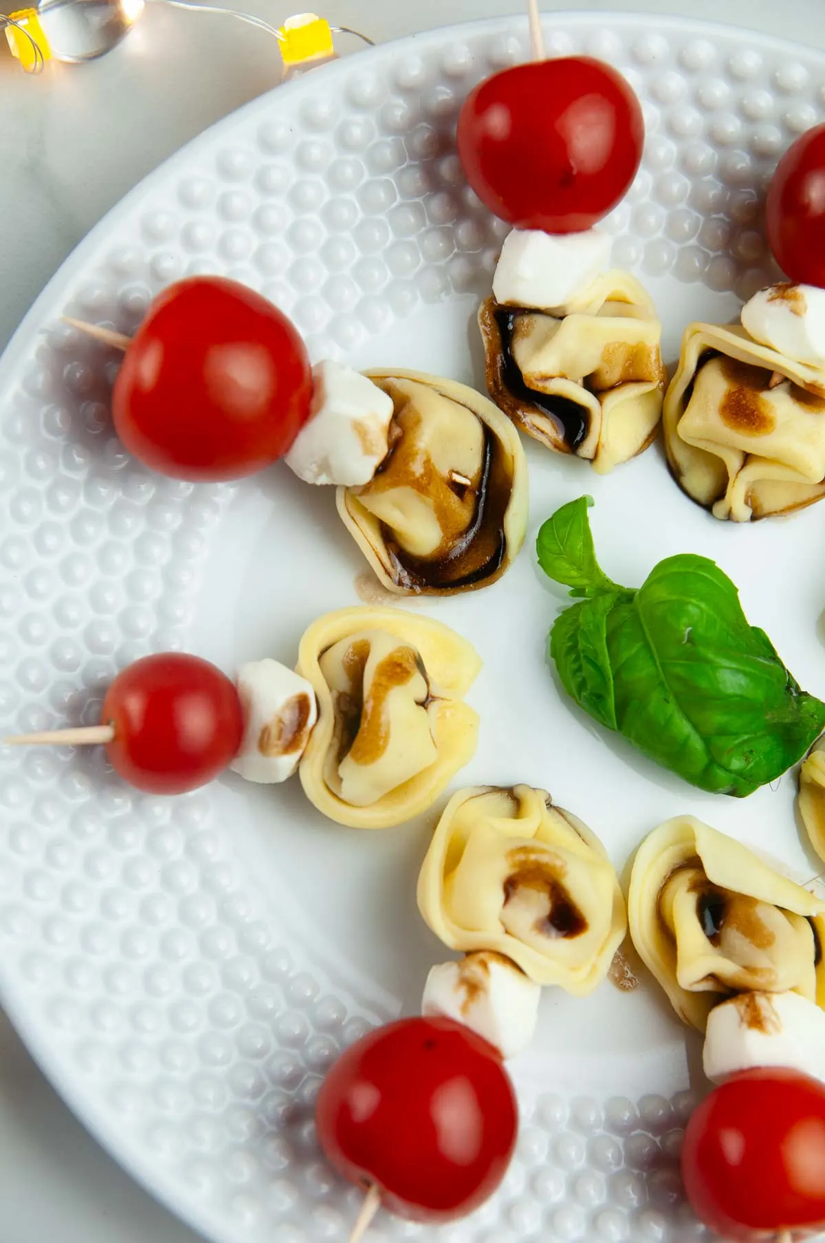 Tortellini Caprese Skewers with balsamic glaze on a white plate