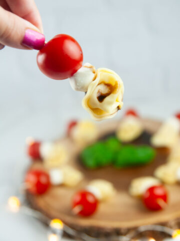 A Tortellini Caprese Skewer being picked up off a serving platter