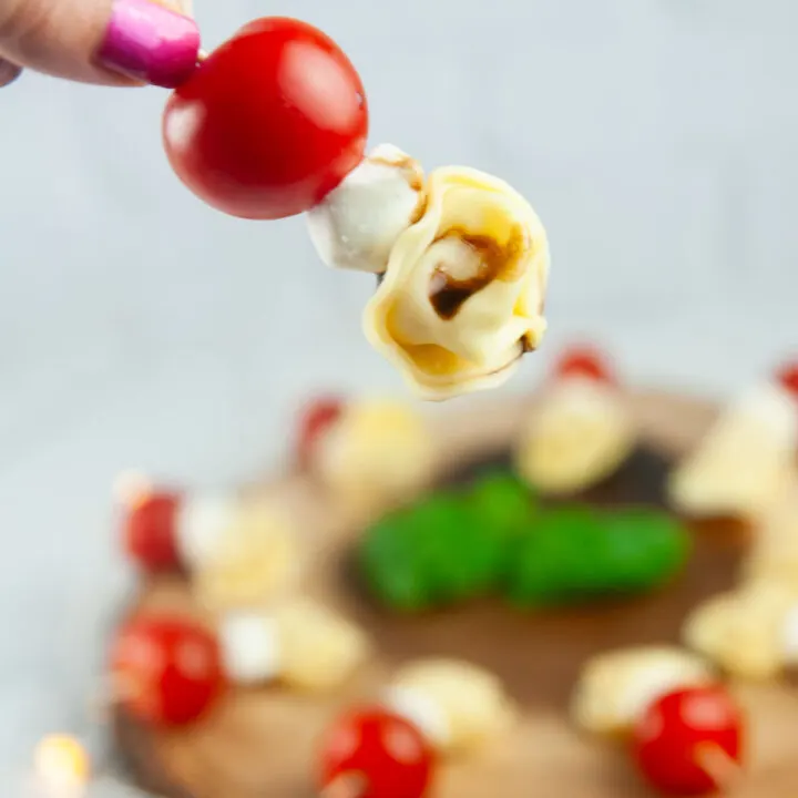 A Tortellini Caprese Skewer being picked up off a serving platter