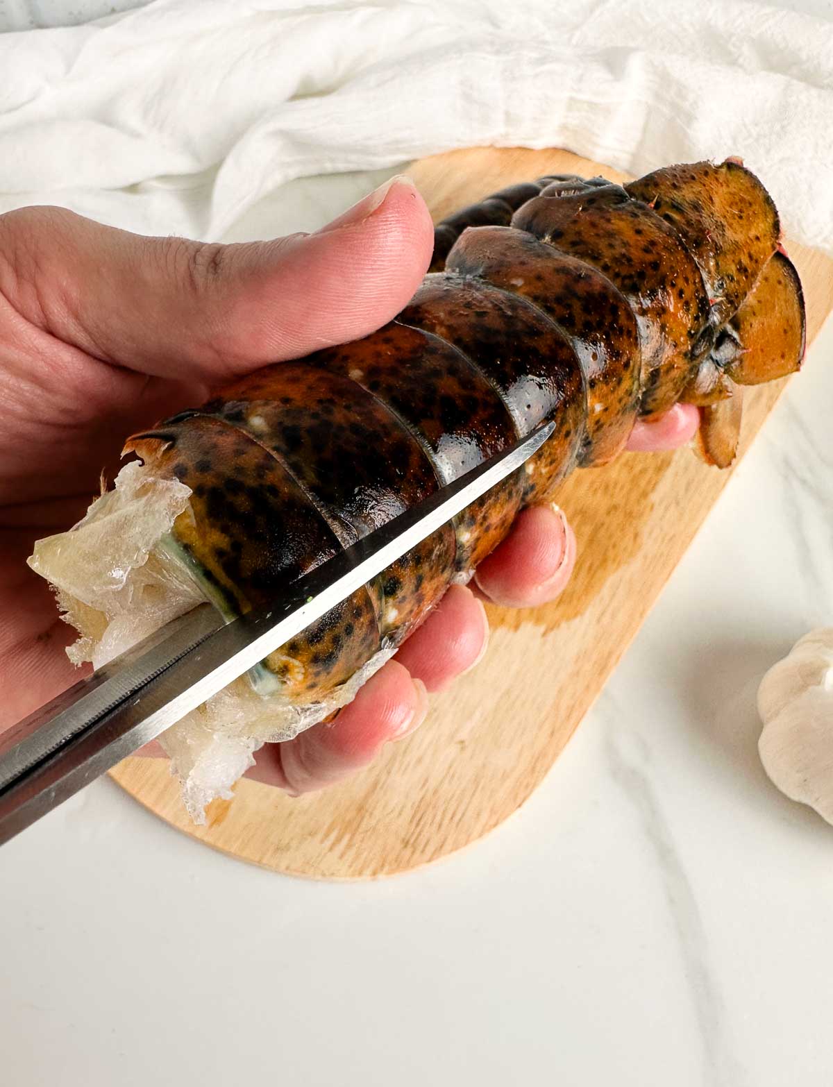 Cut the shell of the lobster tail down the middle with a pair of sharp kitchen shears.