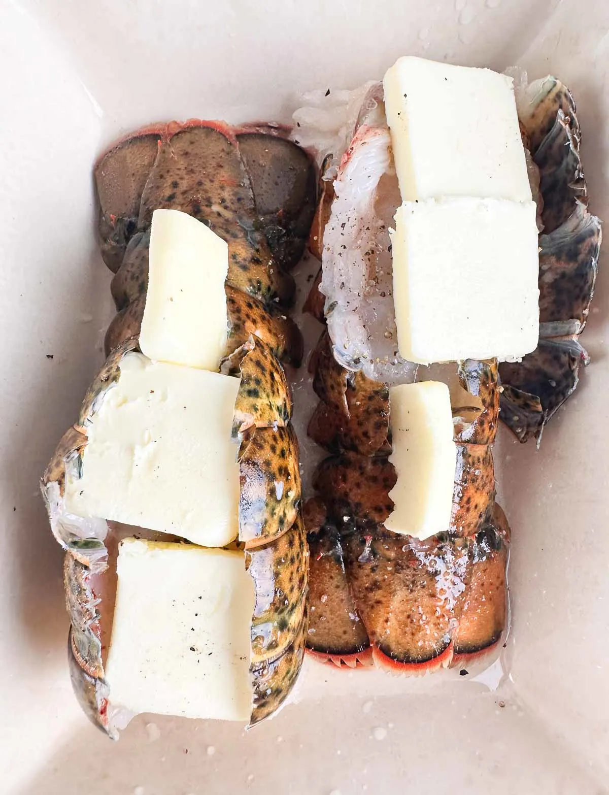 Cover the uncooked lobster meat with pats of butter before roasting it.