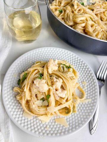 A white plate loaded with creamy lobster alfredo.
