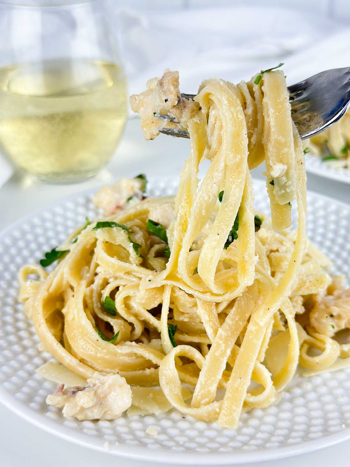 The perfect bite of fettucine Alfredo with lobster on a fork!