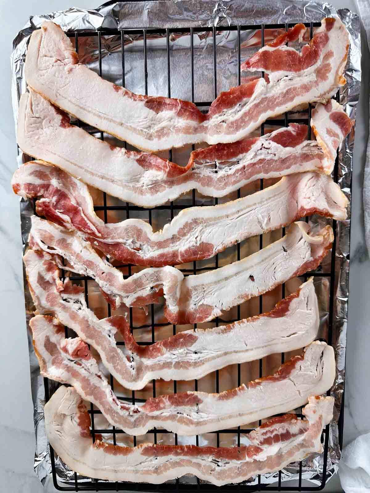 Lay the bacon out over the wire rack set over the prepared cookie sheet.