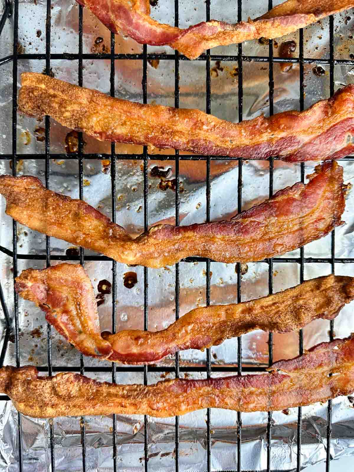 Extra crispy convection oven bacon sitting on a wire rack over a foil lined cookie sheet