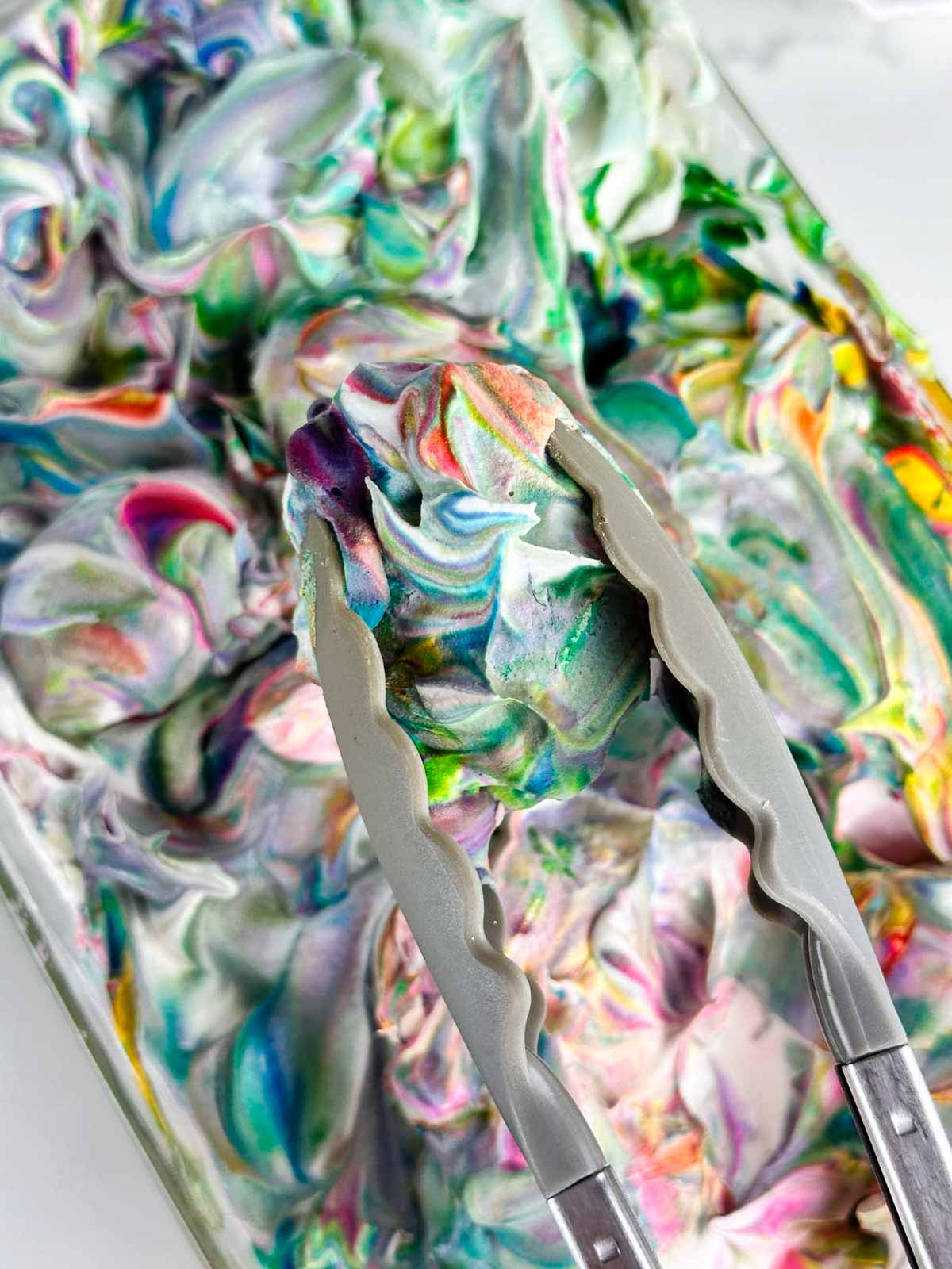 After the eggs have sat in the color swirled Cool Whip, use a pair of tongs to remove them one by one.