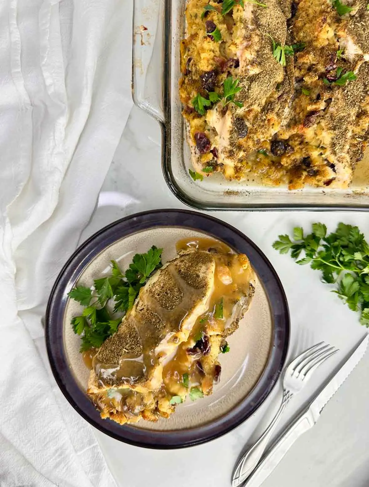 One plated stuffed chicken breast with stuffing and gravy served from a baking dish are ready to be served for dinner.