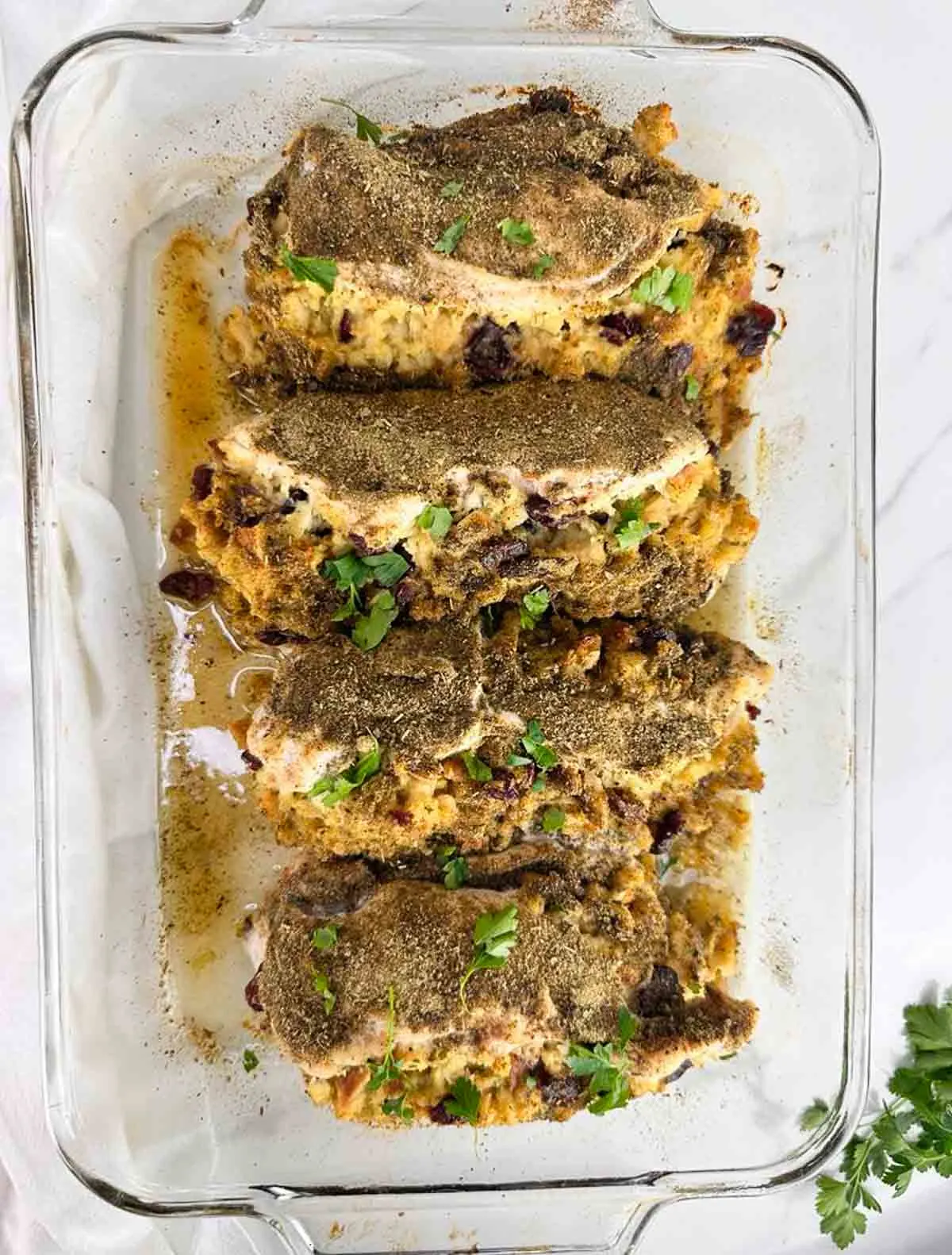 4 stuffed chicken breasts with stuffing in a baking dish are ready to be served for dinner.